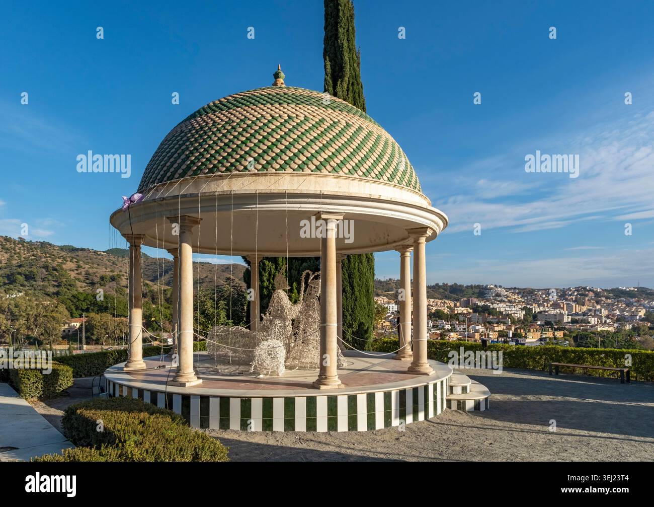 Un classico gazebo con tetto a cupola di colore verde e beige presso il Jardin Botanico Historico la Concepcion, affacciato su una città e colline, Málaga, Spagna Foto Stock