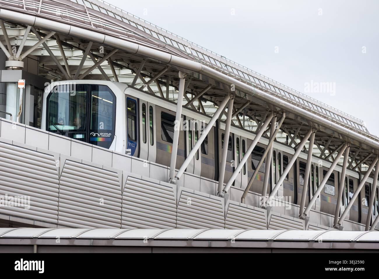Tokyo, Giappone 15 aprile 2026, moderno treno di transito automatizzato yurikamome che viaggia su una struttura ferroviaria sopraelevata con supporti in acciaio e baldacchino della stazione i. Foto Stock