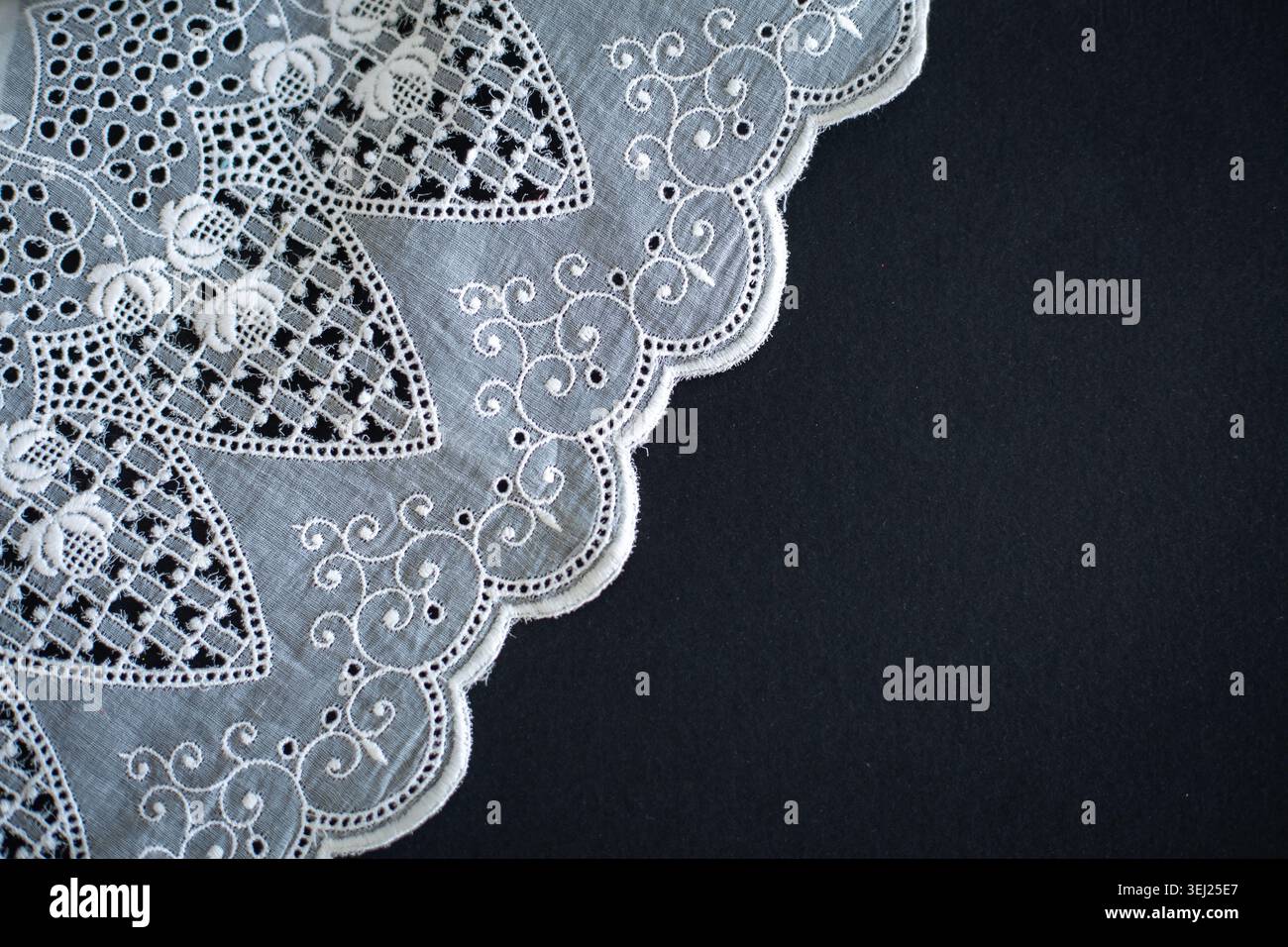 Motivo in pizzo, dettaglio di una tovaglia isolata su sfondo nero. Confine artistico. Artigianato, vintage. Concetto di hobby. Vista dall'alto. Foto di alta qualità Foto Stock