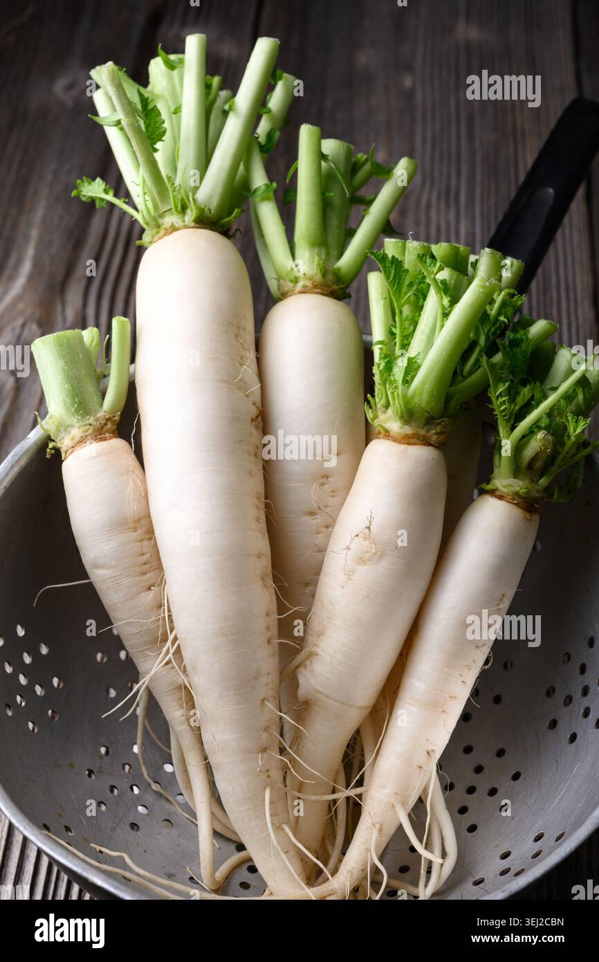Ravanello daikon fresco in colino metallico, ravanello bianco, verdure lavate Foto Stock
