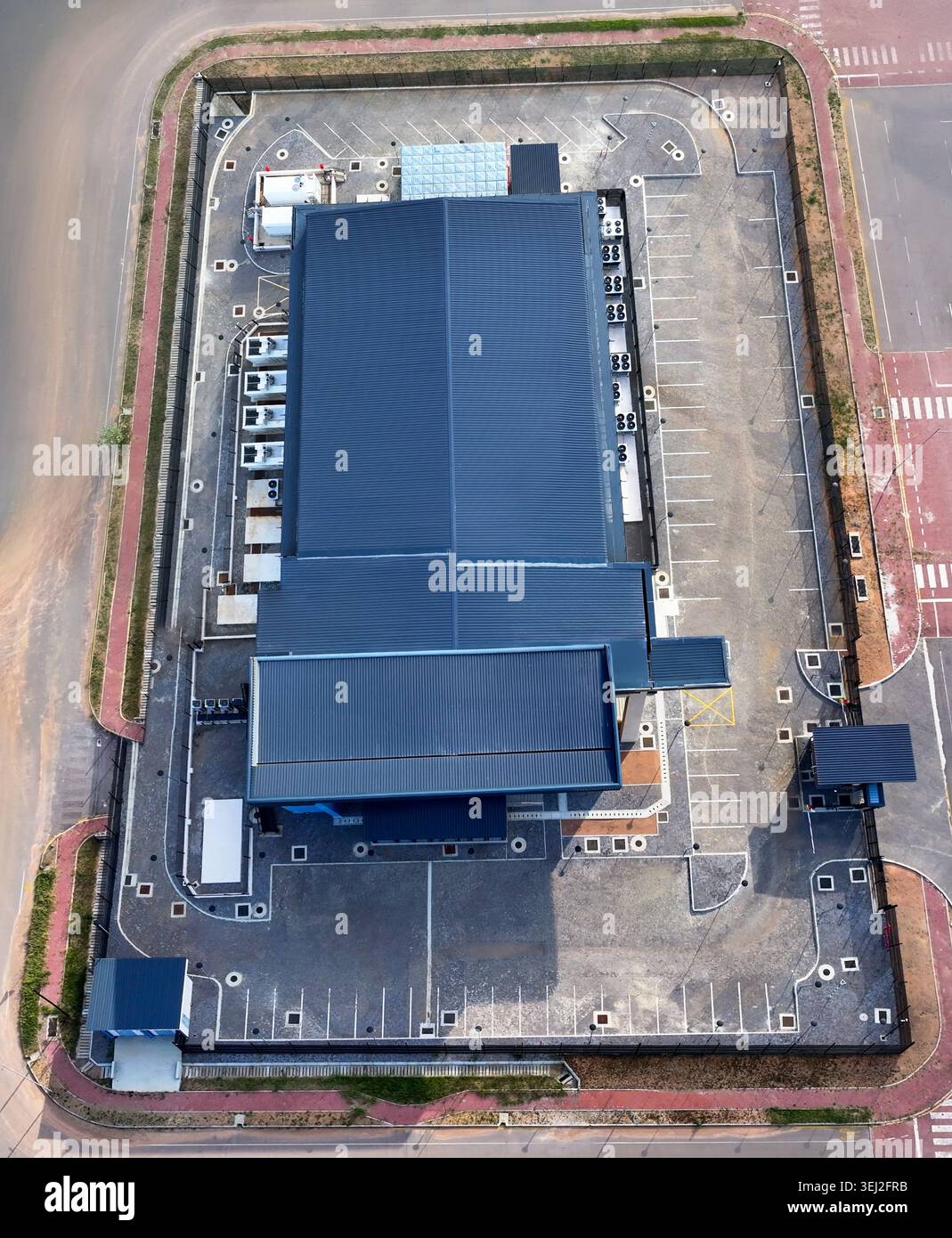 Ripresa aerea di un impianto industriale sicuro, il data center , con un'enorme banca di condensatori HVAC industriali che rivestono la parete laterale e combustibile di riserva Foto Stock