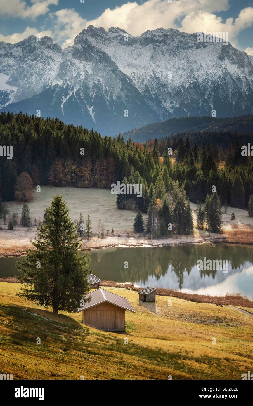 Paesaggio pittoresco in un lago nelle Alpi tedesche, con montagne e capanne su un prato giallo al sole Foto Stock