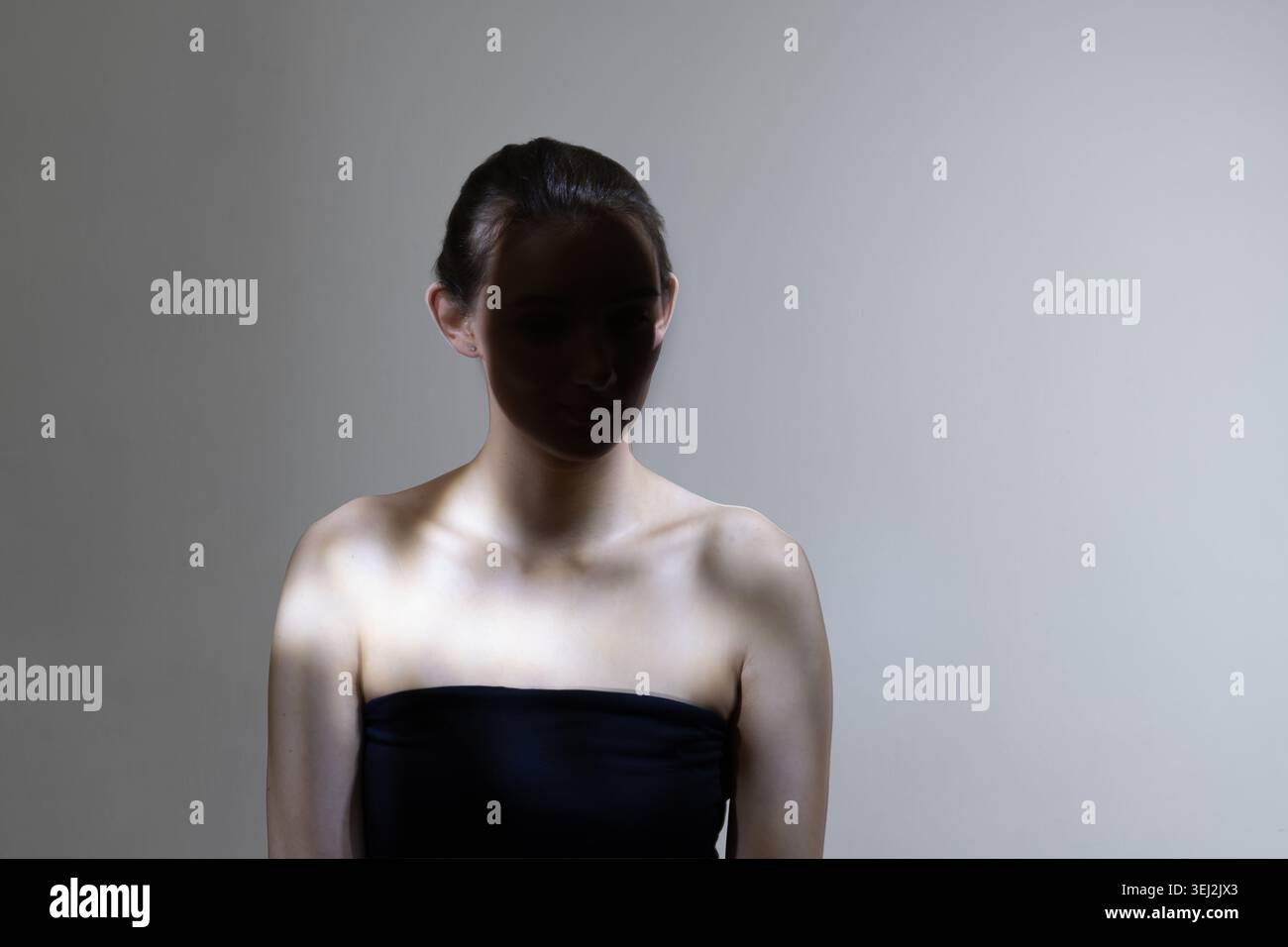 Ritratto di donna con volto in ombra che esprime anonimato e identità nascosta Foto Stock