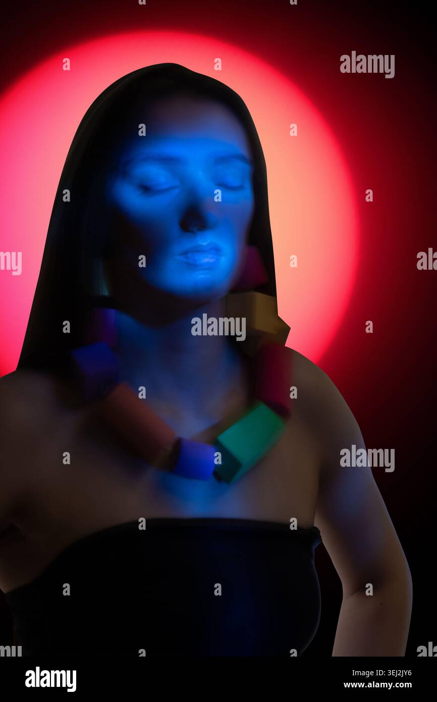 Il viso della donna si illumina di blu a occhi chiusi, meditando con una collana colorata Foto Stock