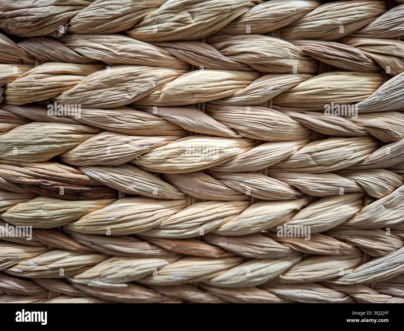Questo primo piano mostra una consistenza intrecciata di vimini marrone chiaro naturale fatto di fibre vegetali essiccate. L'immagine visualizza il modello intrecciato organico e il detai Foto Stock