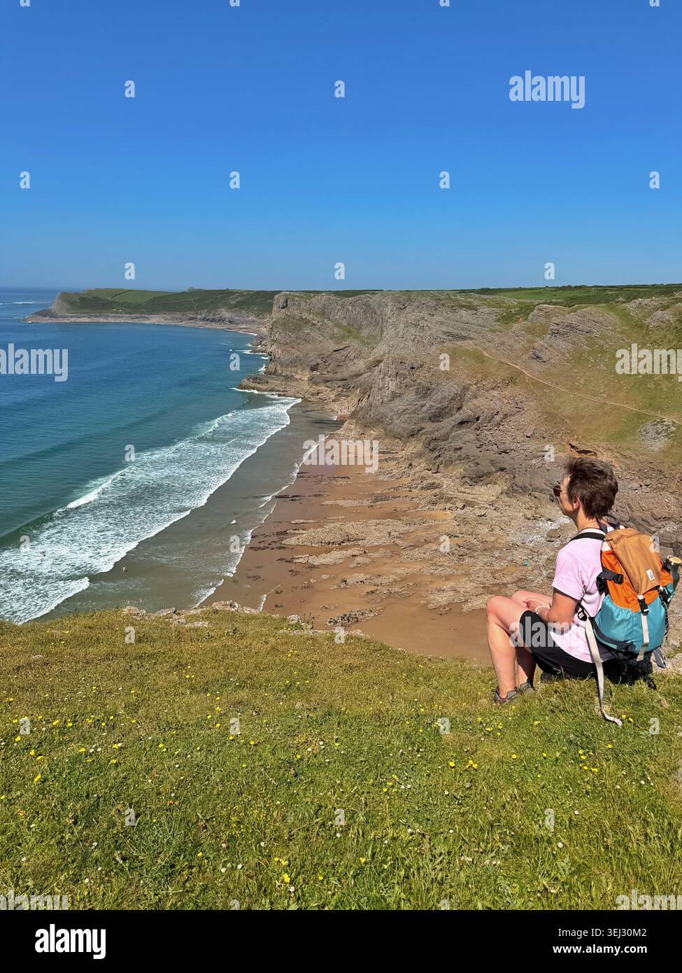 Donna di mezza età che gode della vista sulla baia, sulla baia di Mewslade, da Thurba Head, Gower, Swansea, Galles, Regno Unito - Immagine stock catturata con smartphone