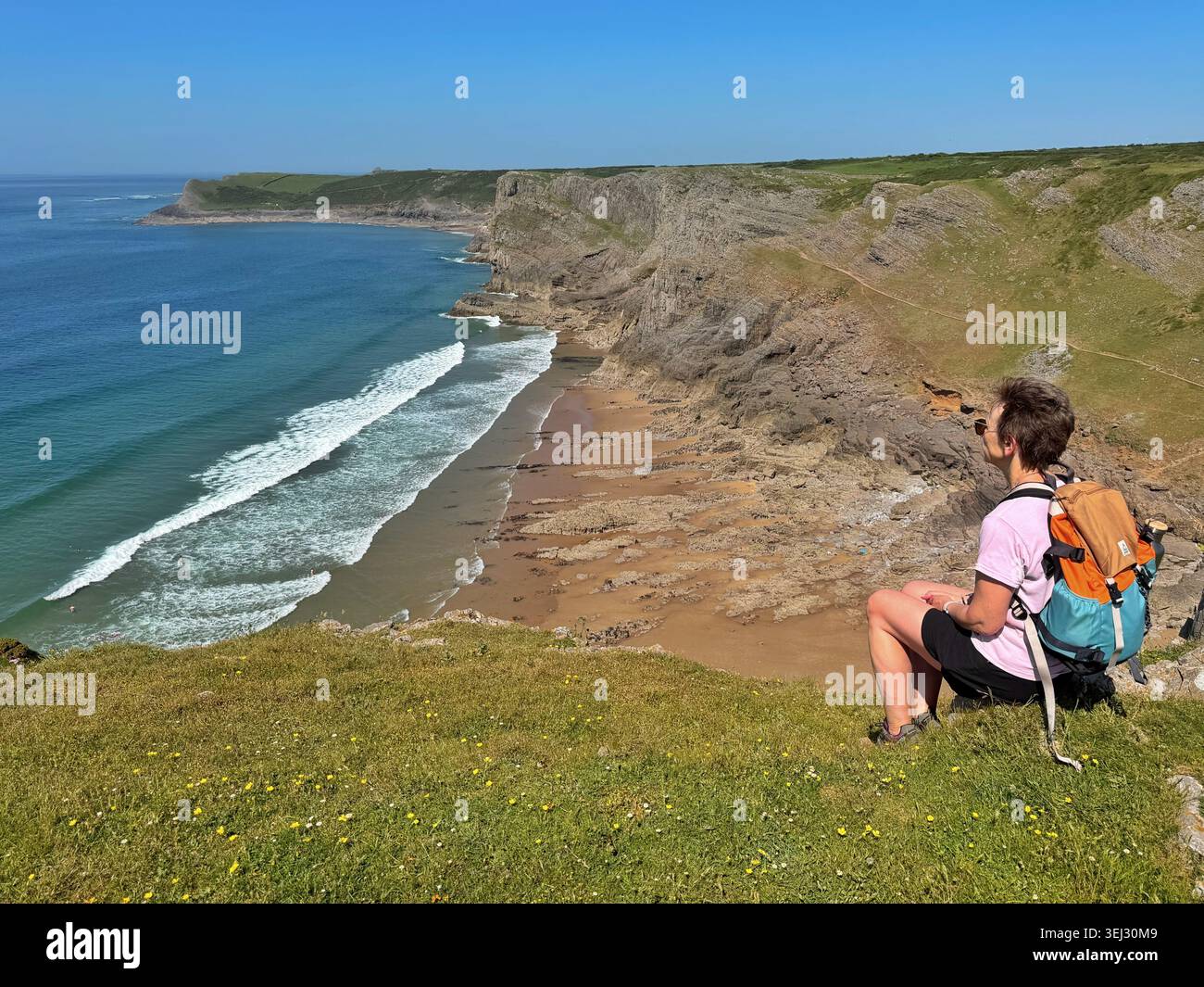 Donna di mezza età che gode della vista sulla baia, sulla baia di Mewslade, da Thurba Head, Gower, Swansea, Galles, Regno Unito - Immagine stock catturata con smartphone