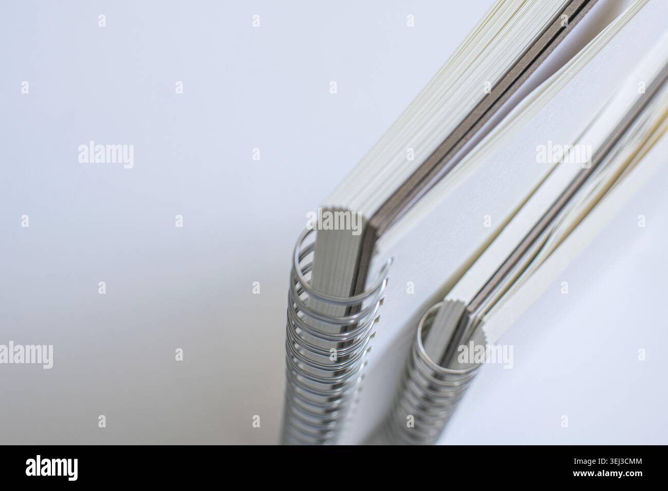 Dettagli macro della rilegatura a spirale del notebook e dei bordi della carta sulla superficie bianca in studio. Articoli di cancelleria minimali, editoria moderna, branding elegante, creatività Foto Stock