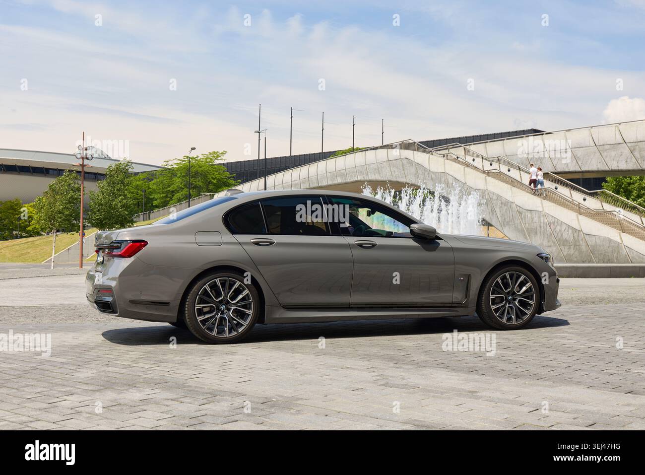 BMW 740D. Un'auto di lusso si trova vicino ad un edificio contemporaneo con una fontana. Il profilo elegante mette in risalto le linee eleganti e il design sofisticato Foto Stock