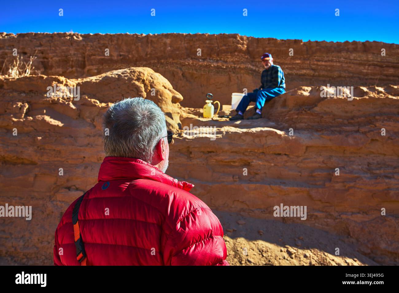 Geologia discussione sul campo in Desert Landscape con Rock Layers e due uomini Foto Stock