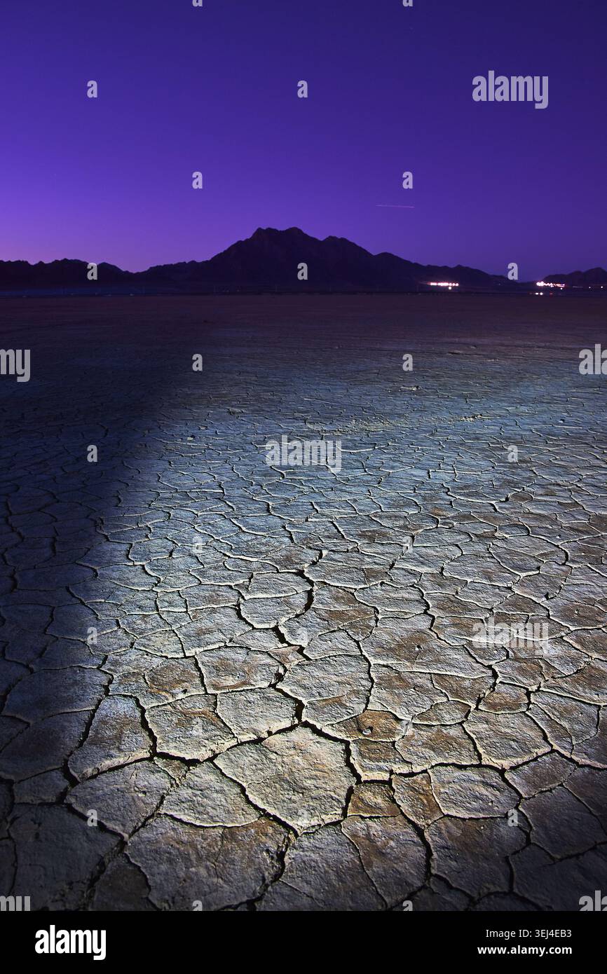 Letto Cracked Dry Lake al Twilight con le lontane montagne del Nevada e il Purple Sky Foto Stock