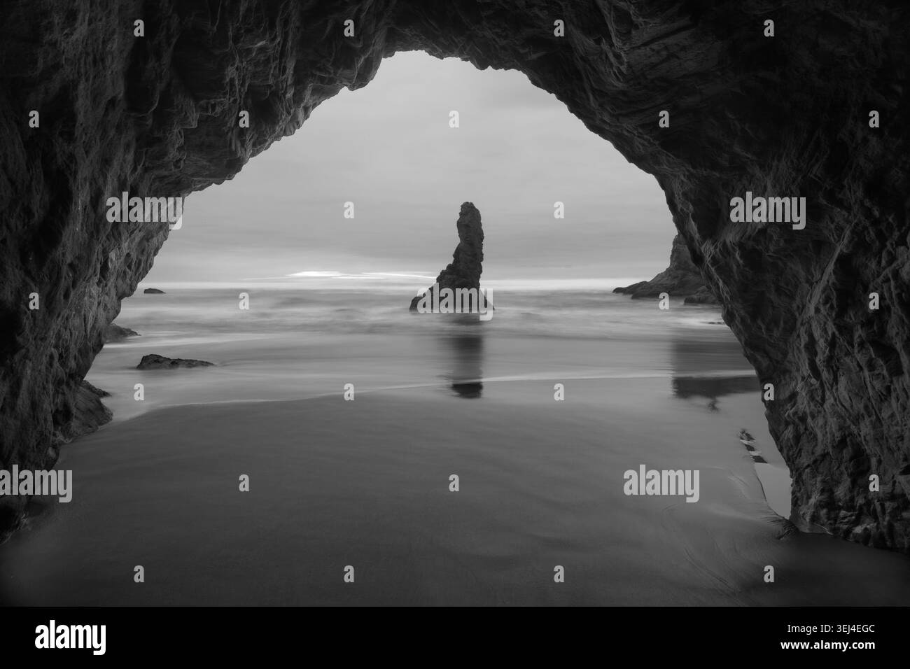 Una spettacolare fotografia monocromatica ad alto contrasto scattata dall'interno di una grotta marina naturale scura a arco a Bandon Beach lungo la parte meridionale di Oreg Foto Stock