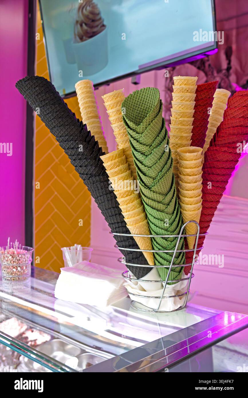 I coni di gelato colorati con waffle sono esposti in una vetrina di pasticceria Foto Stock