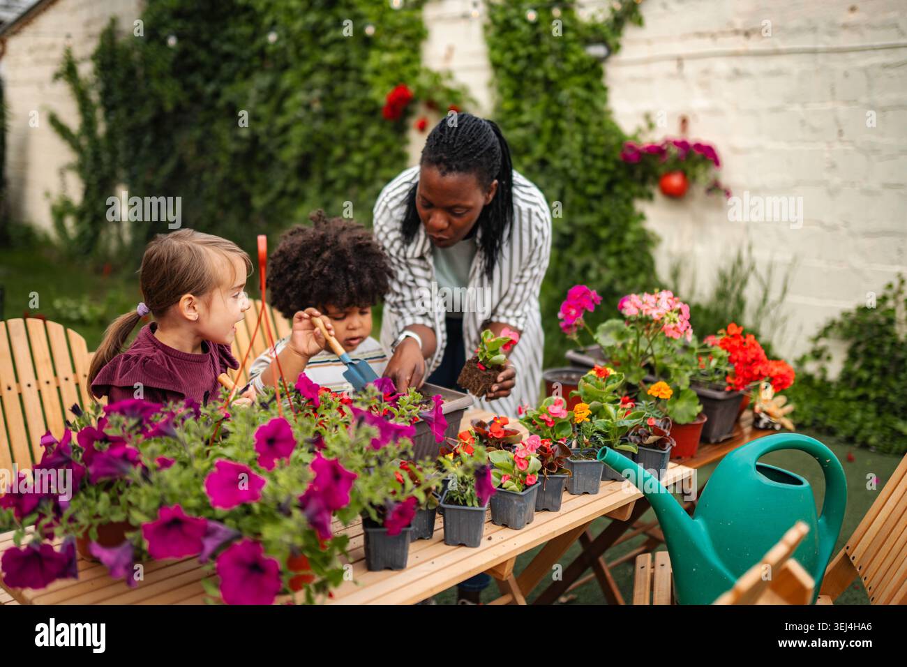 Famiglia che impara le abilità di giardinaggio insieme nel giardino di casa Foto Stock