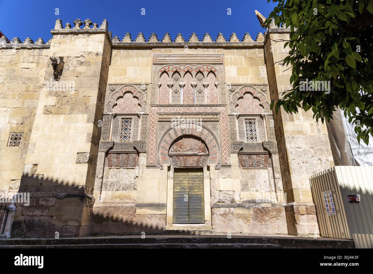 La facciata dettagliata della Mezquita-Catedral presenta intricati lavori in pietra e archi che brillano al sole Foto Stock