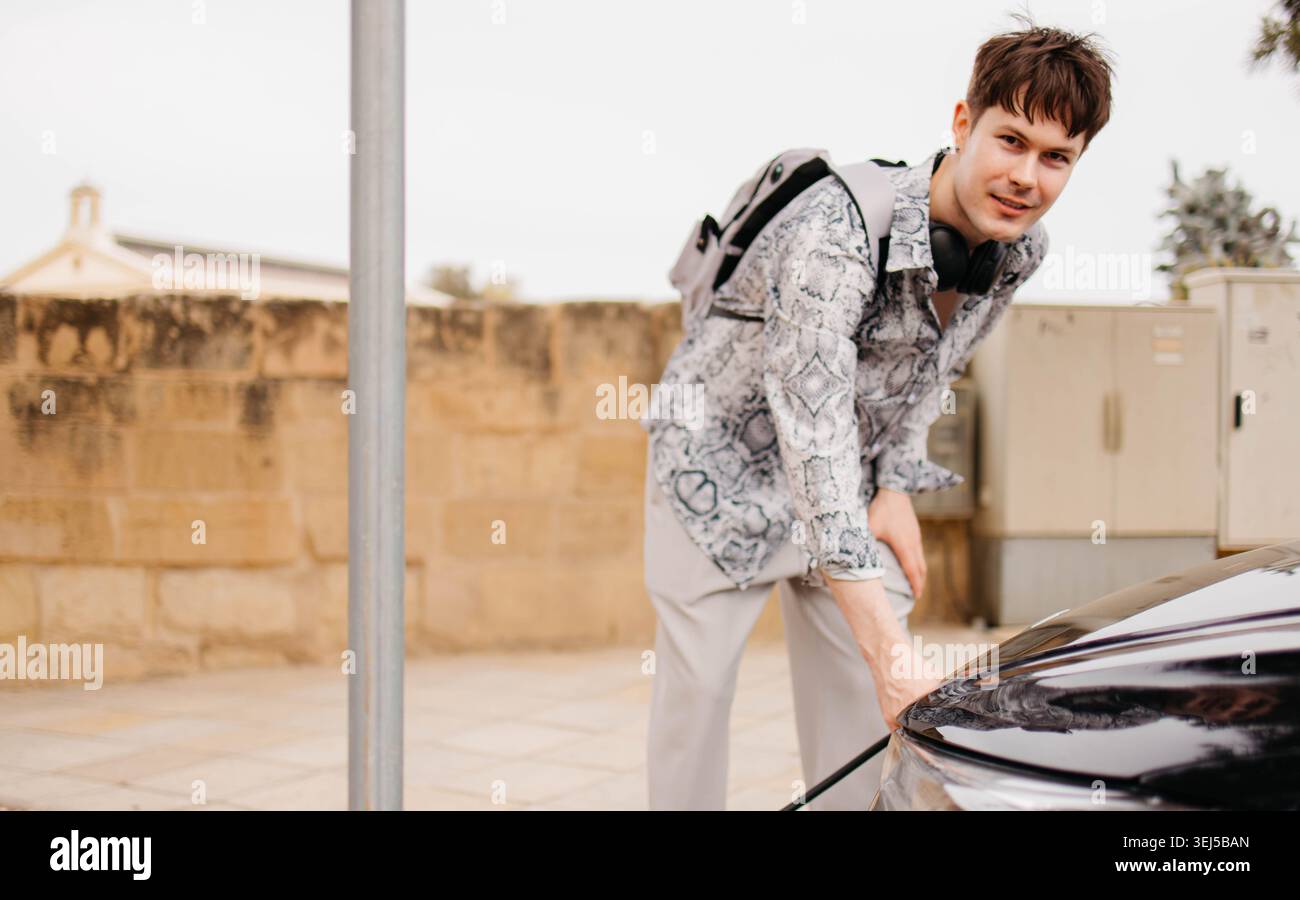 Proprietario di un'auto che ricarica un'auto elettrica Foto Stock