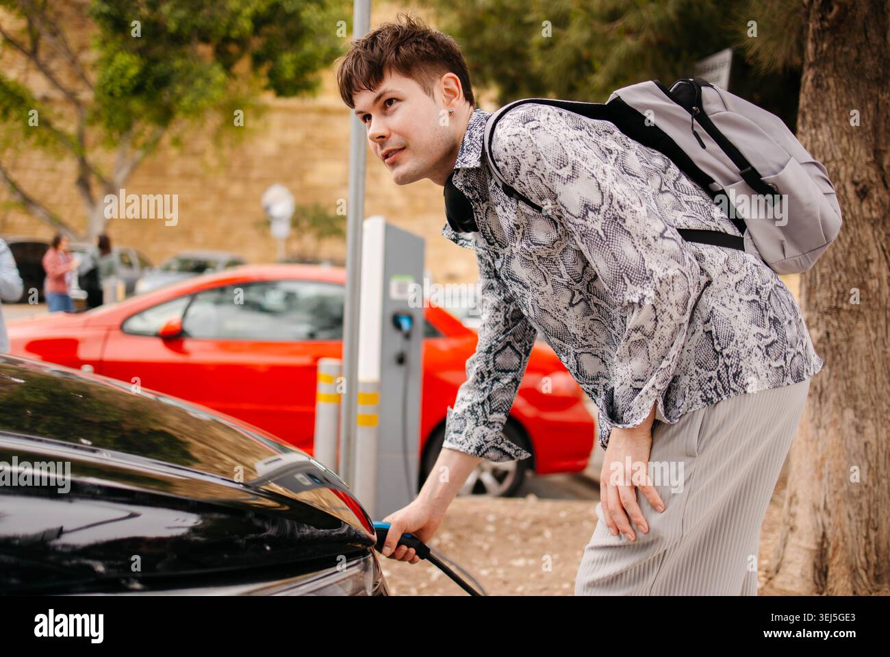 Proprietario di un'auto che ricarica un'auto elettrica Foto Stock