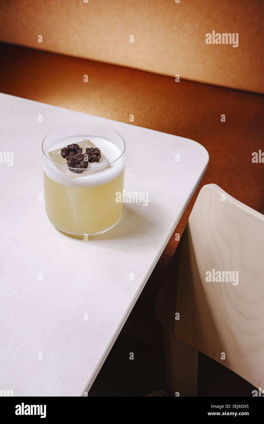 Cibo, Un bellissimo cocktail si siede su un tavolo moderno accanto a una sedia di legno, mostrando ingredienti unici e una presentazione creativa in un ambiente caldo e invitante Foto Stock