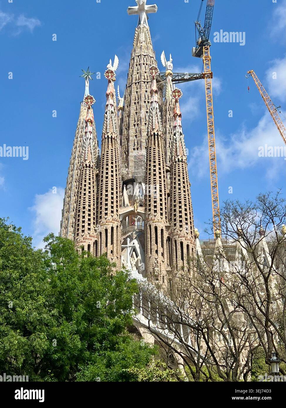 Barcellona, Spagna - 22 aprile 2026: Le torri della Sagrada Familia si innalzano sopra gli alberi alla luce del giorno. - Immagine stock catturata con smartphone