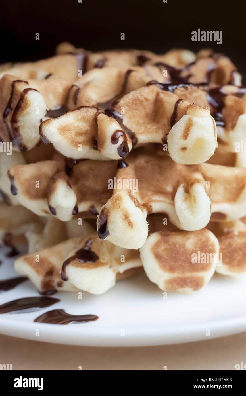 Vista macro dei waffle viennesi conditi con sciroppo al cioccolato, orientamento verticale Foto Stock