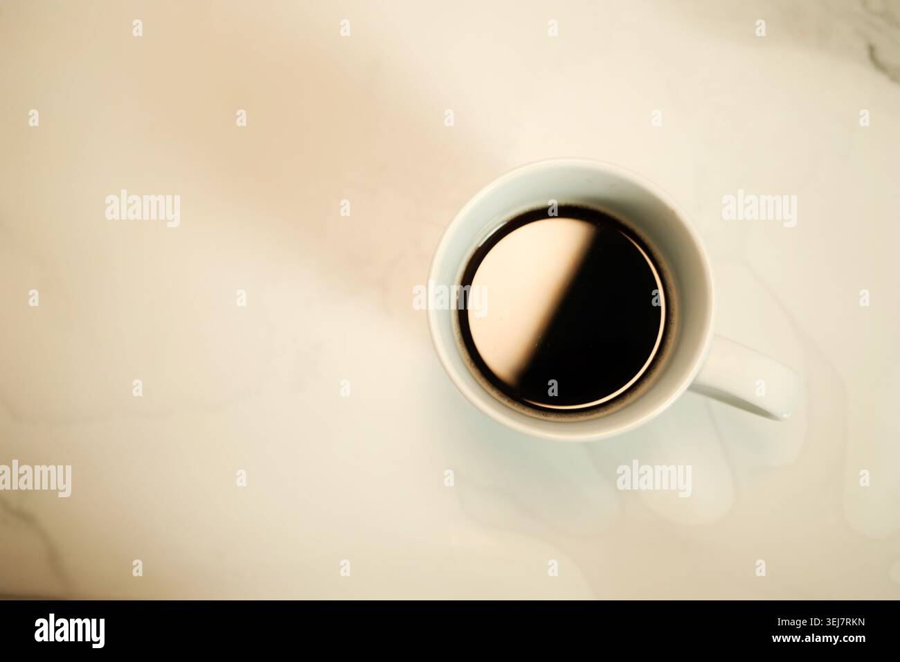 Elegante vista dall'alto del caffè scuro all'interno di una tazza in ceramica bianca con ombre soffuse alla luce del sole. Estetica minimale del caffè e concetto di stile di vita tranquillo. Foto Stock
