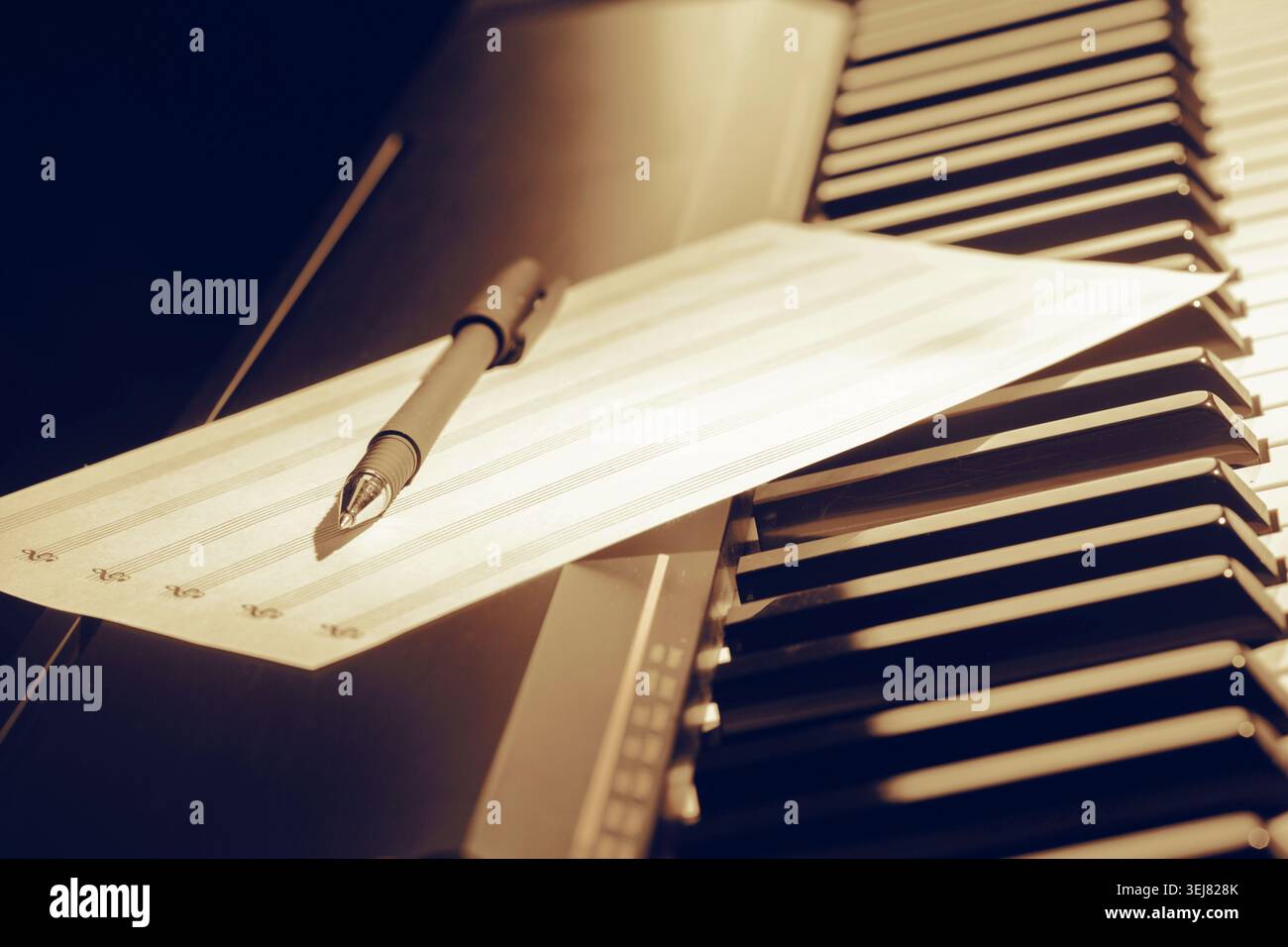 Scrivere appunti musicali su carta mentre si è seduti al pianoforte in una stanza soffusa Foto Stock