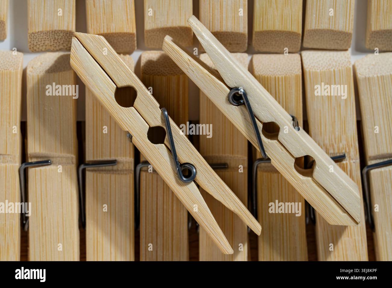 Sfondo clothespin in legno con due perni in legno. Primo piano di due clothespins di bambù o di legno leggeri che giacciono sulla sommità di una fila organizzata di lau simili Foto Stock