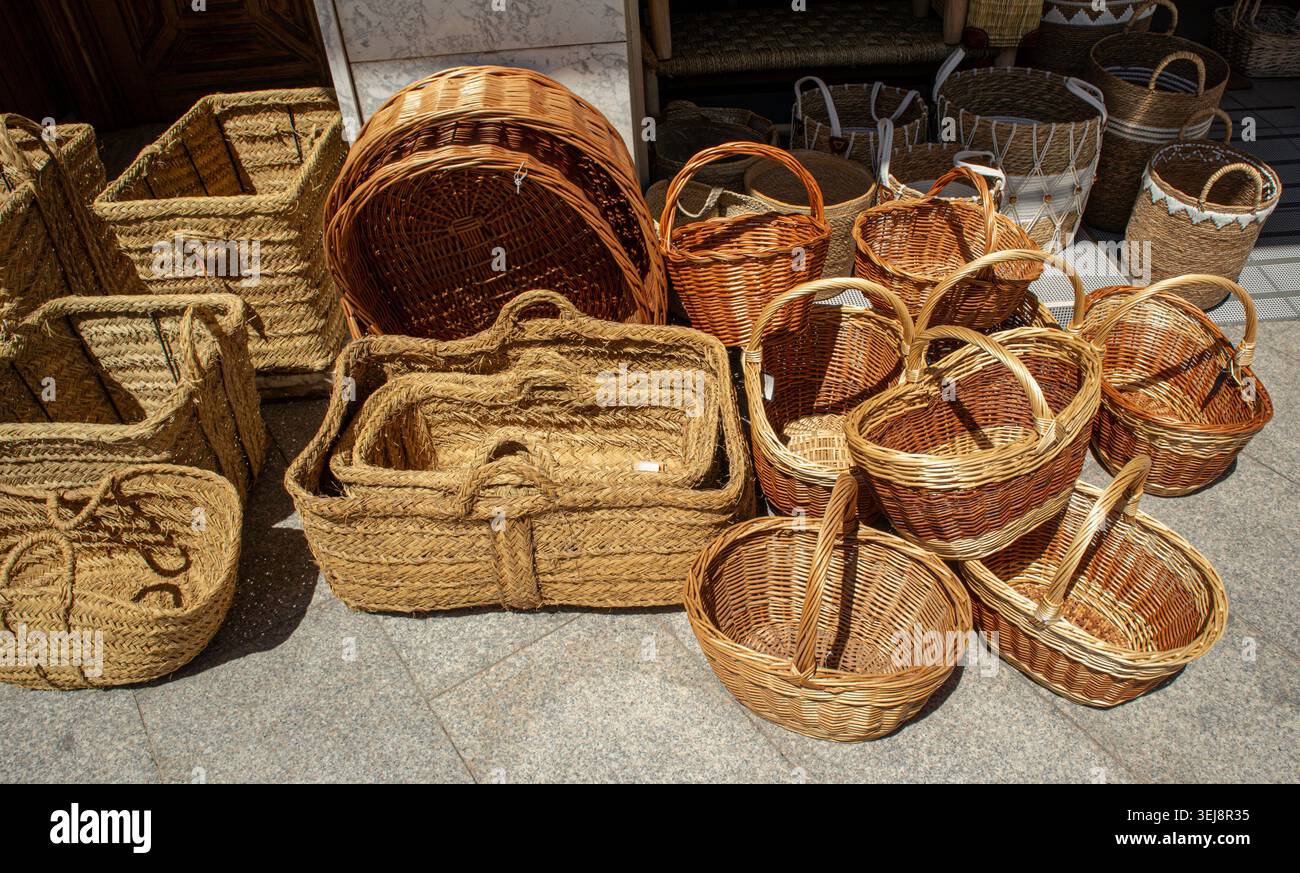 Una varietà di cestini in tessuto è in vendita per la strada. I cestelli sono fatti di salice e paglia. Gli acquirenti esplorano le opzioni in un mercato affollato Foto Stock
