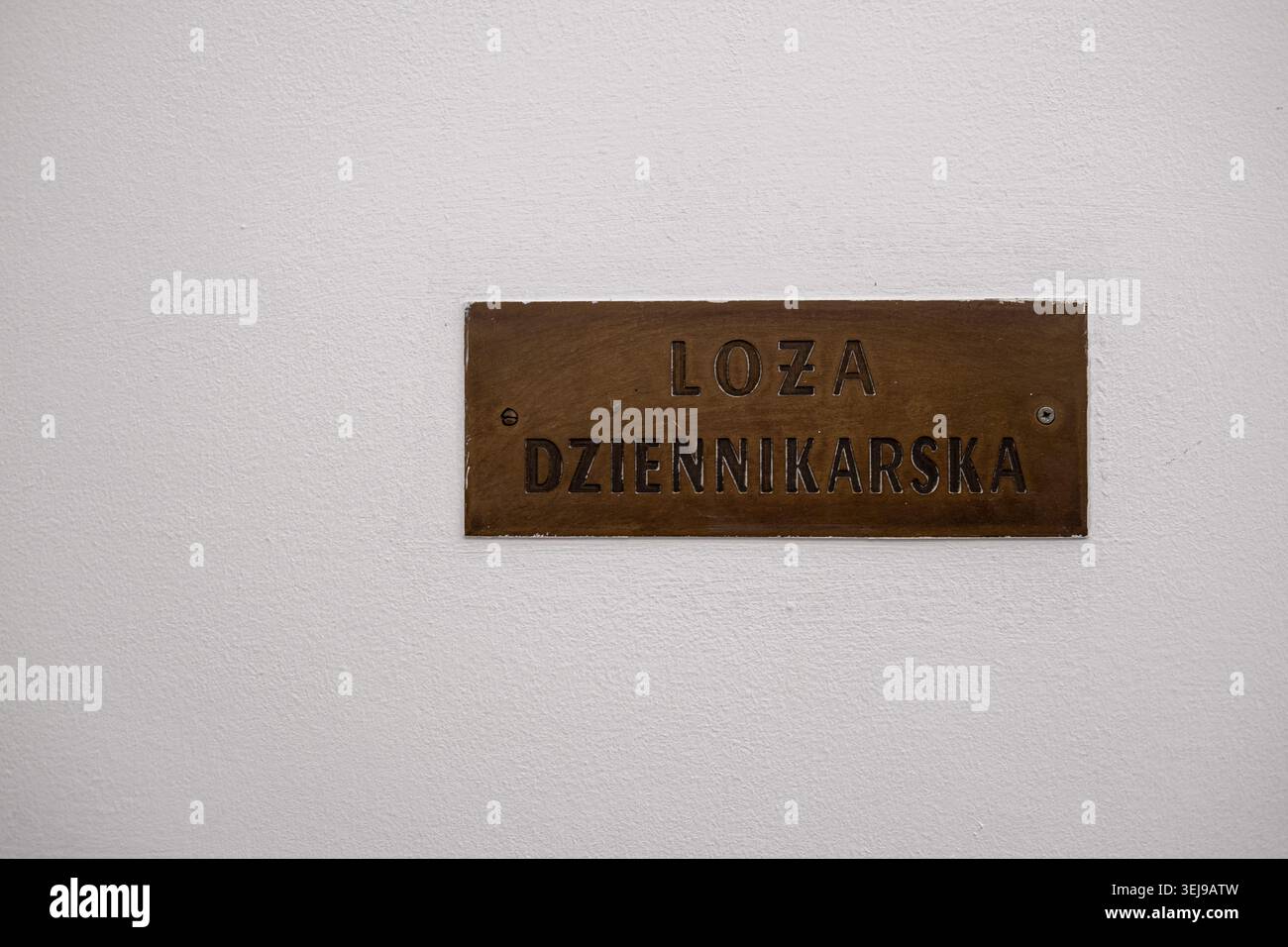 Una targa di ottone con la scritta Loża Dziennikarska è montata su una parete bianca del parlamento polacco. Foto Stock