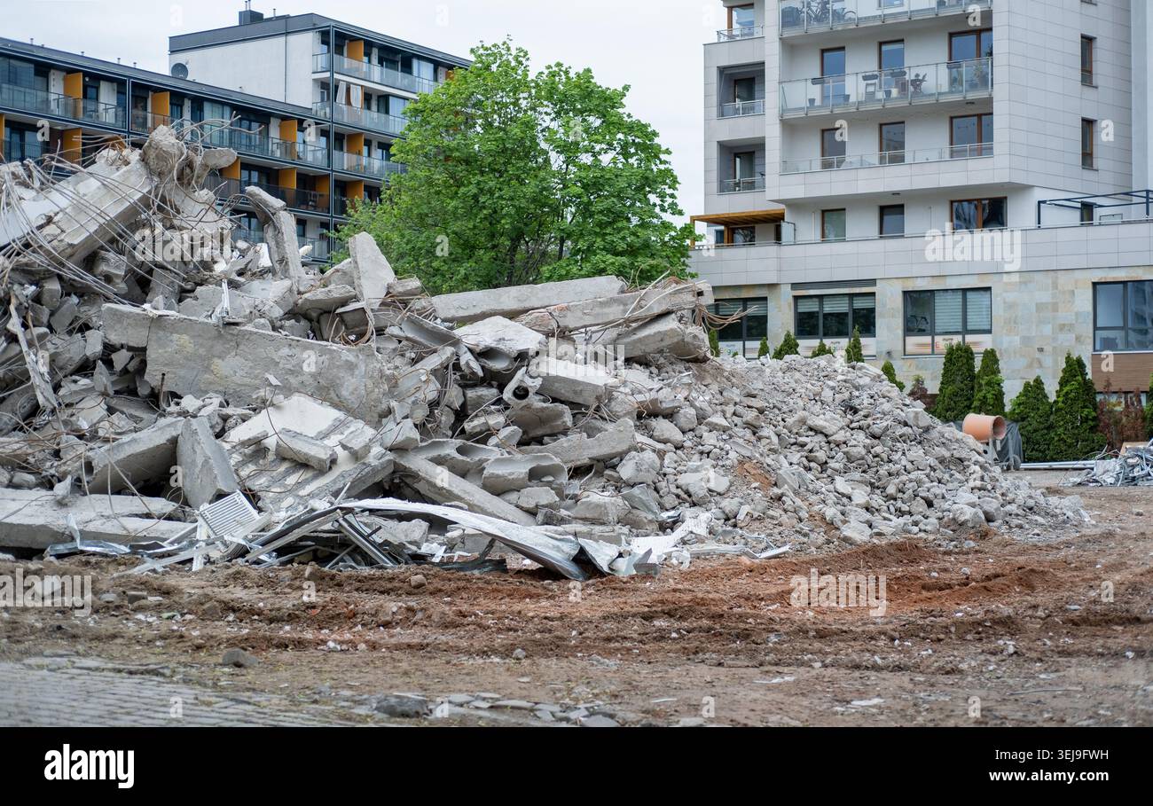 Un mucchio di macerie di cemento demolite di fronte ad un moderno edificio residenziale. Foto Stock