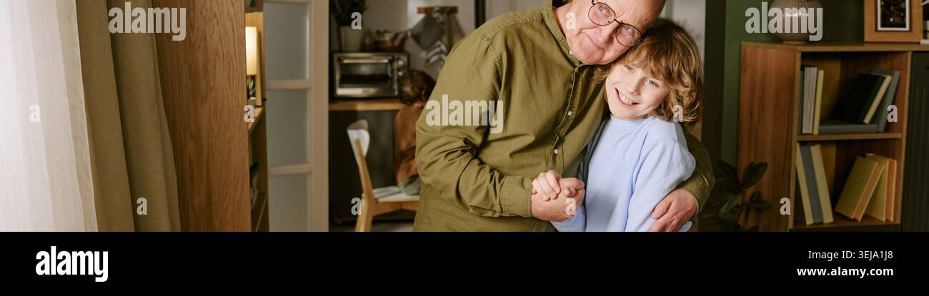 Intestazione di Senior Man Heging Child at Home per Family Care Foto Stock