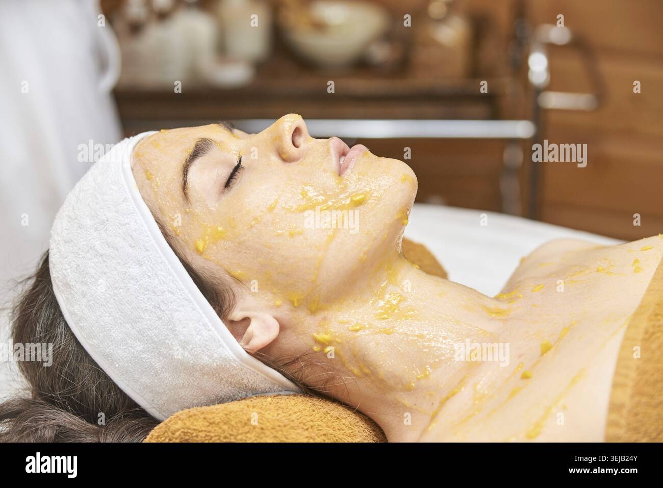 Giovane donna caucasica che riceve un trattamento viso con maschera di miele presso la Spa, che mette in evidenza il relax e la routine SkinCare Foto Stock