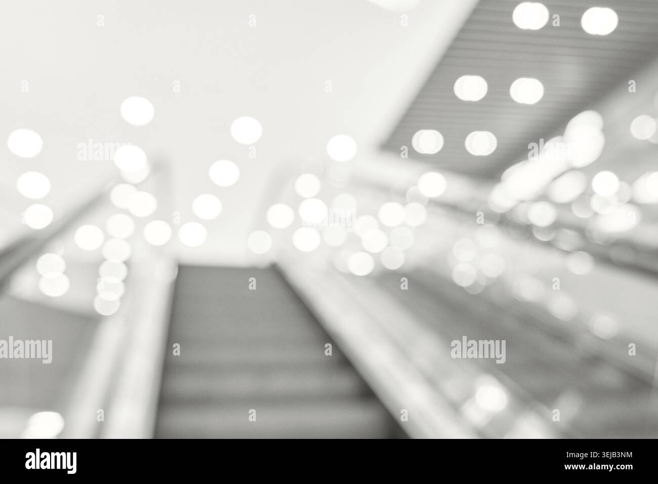 Immagine astratta sfocata di scala mobile con luci bokeh luminose nel moderno centro commerciale Foto Stock