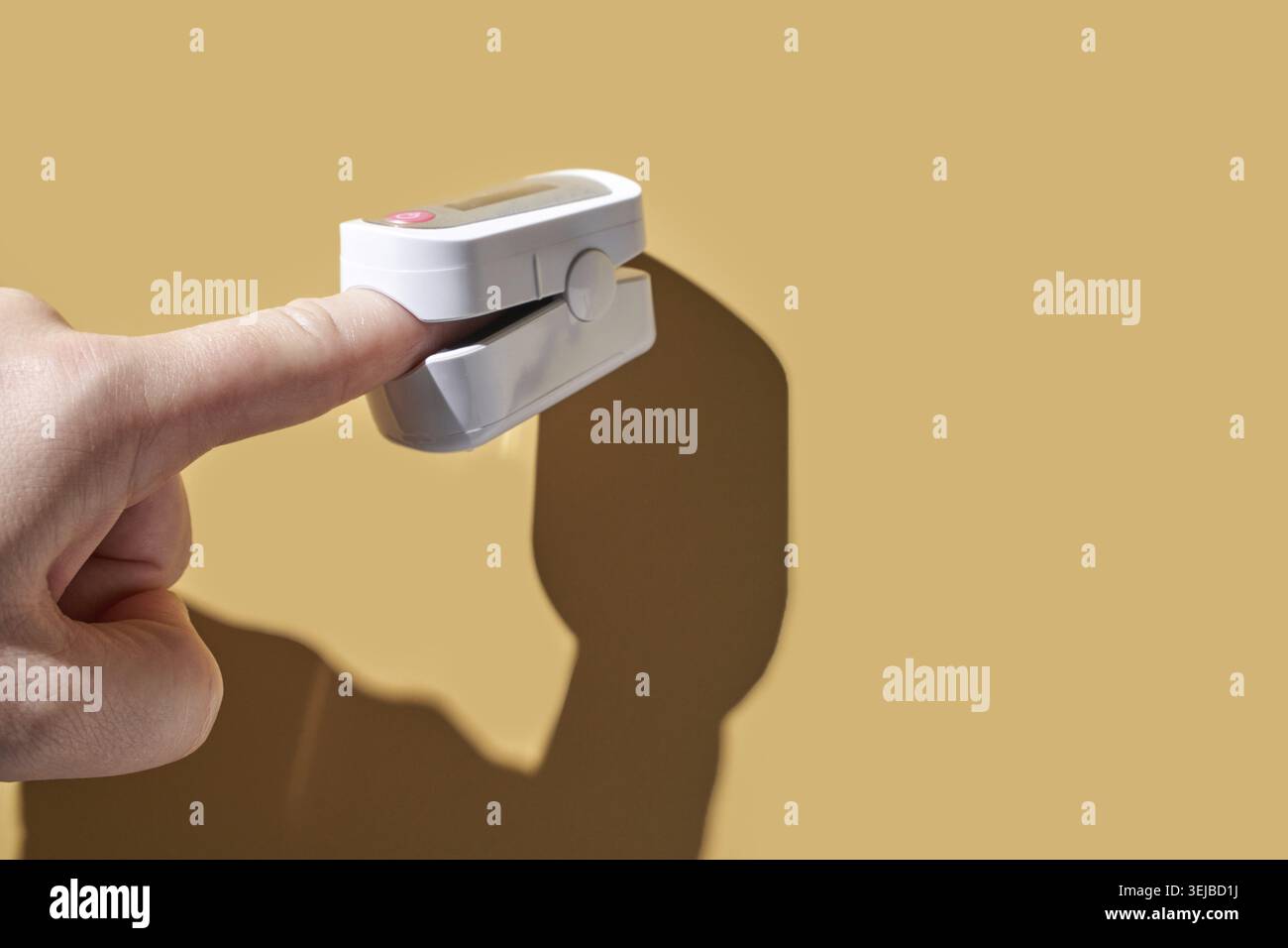 Dito caucasico per adulti che utilizza pulsossimetro su sfondo marrone per il monitoraggio sanitario Foto Stock