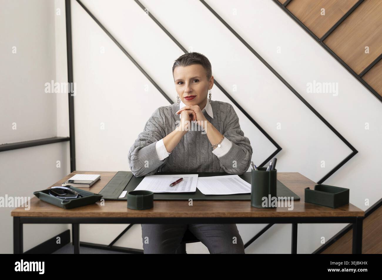 Donna d'affari matura e premurosa seduta dietro i documenti in ufficio Foto Stock