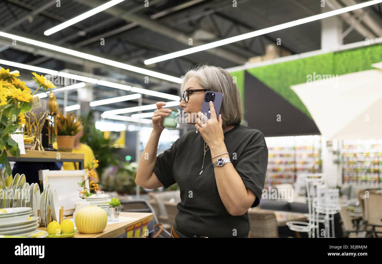 Una donna di mezza età interagisce con i prodotti in un ipermercato delle costruzioni Foto Stock