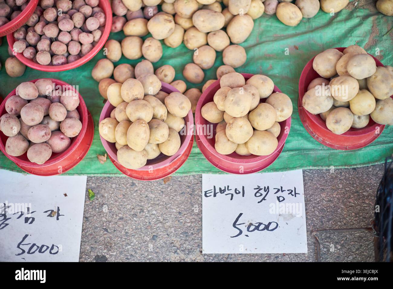 Le foto mostrano pesche all'inizio dell'estate in casse gialle e patate novelle in ciotole rosse in un mercato locale, catturando l'autentico fascino del prodo crudo di stagione Foto Stock