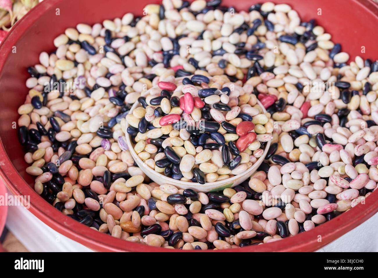 I fagioli colorati riempiono i bacini rossi di un mercato coreano. Queste foto vivaci evidenziano il fascino autentico del commercio agricolo locale. Foto Stock