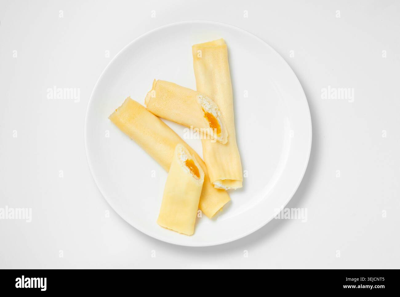 Pancake sottili arrotolati dolci tagliati a metà con formaggio di casa e confettura d'arancia Foto Stock