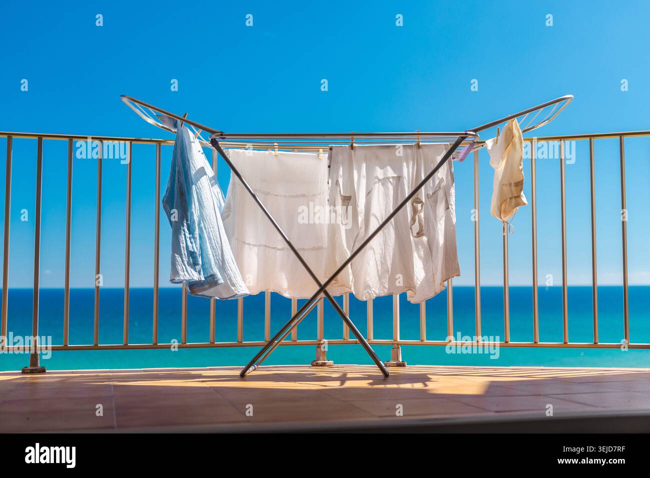 Lavanderia su balcone con vista mare turchese nelle soleggiate giornate estive presso l'appartamento sulla spiaggia vicino alla costa oceanica Foto Stock