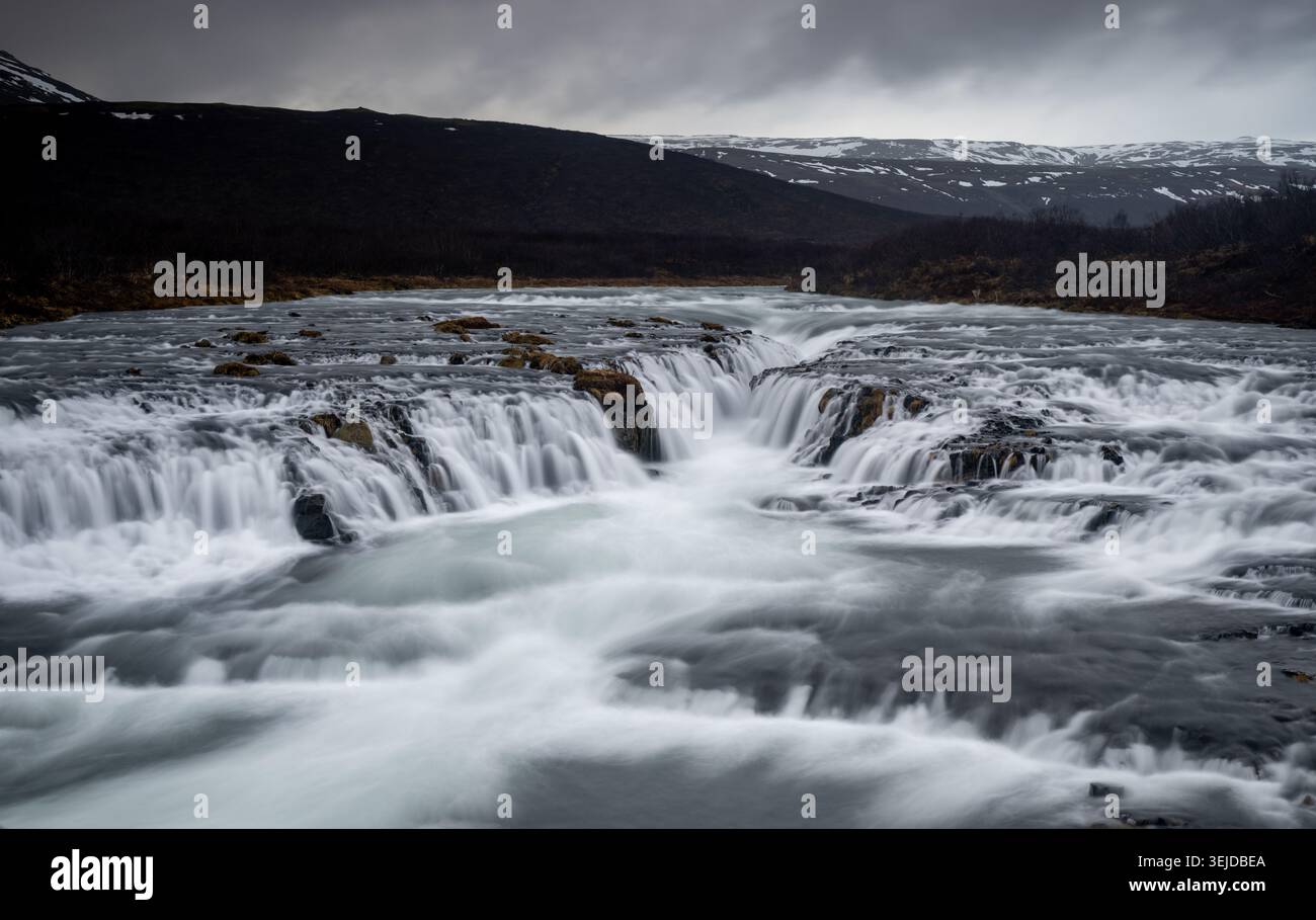 La cascata di Bruarfoss, che mostra acque turchesi che si tuffano su rocce scure in un aspro paesaggio nordico, il Circolo d'Oro dell'Islanda Foto Stock