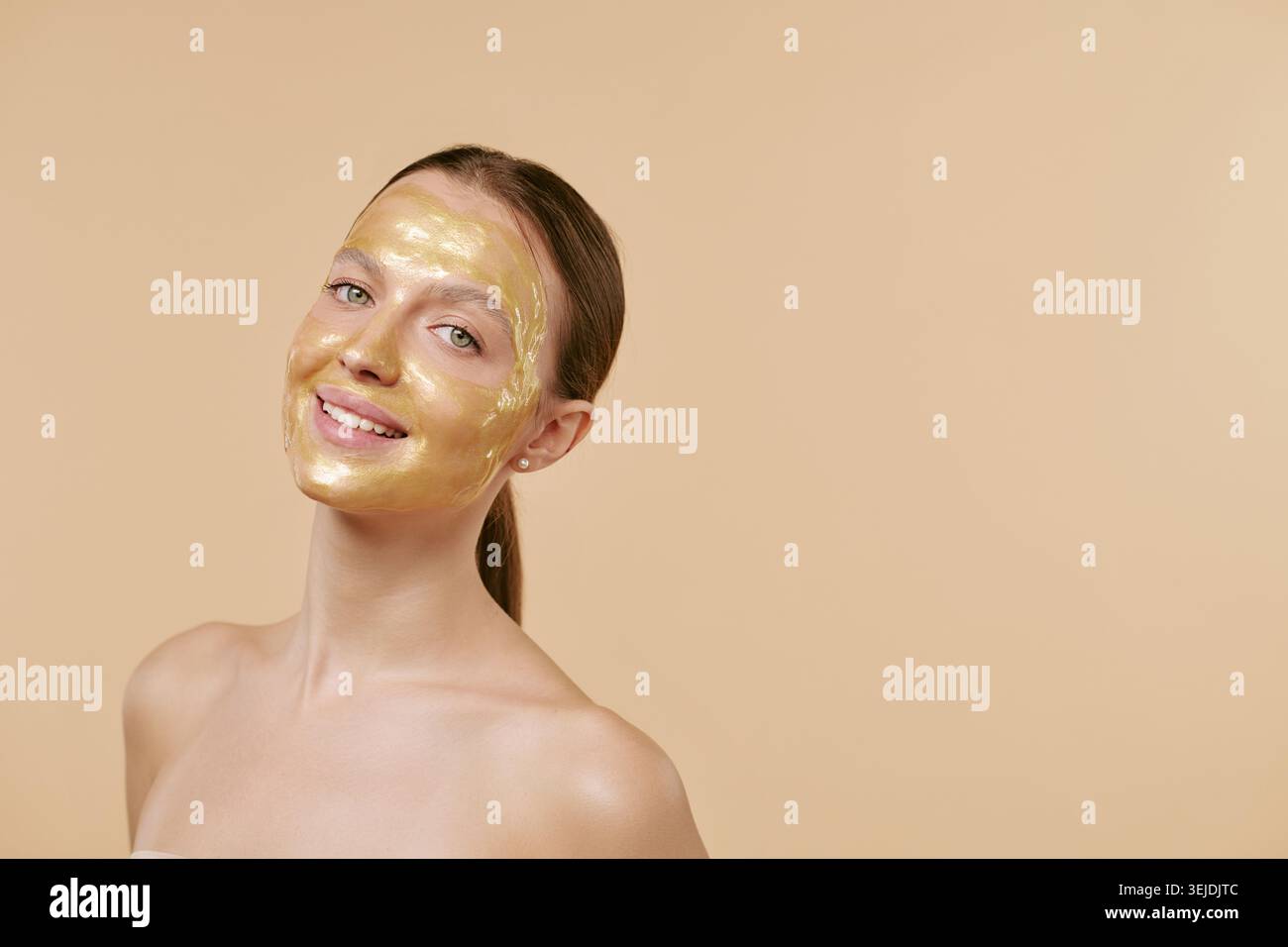 Ritratto di donna adulta che sorride in Gold Face Mask per la campagna Spa Foto Stock
