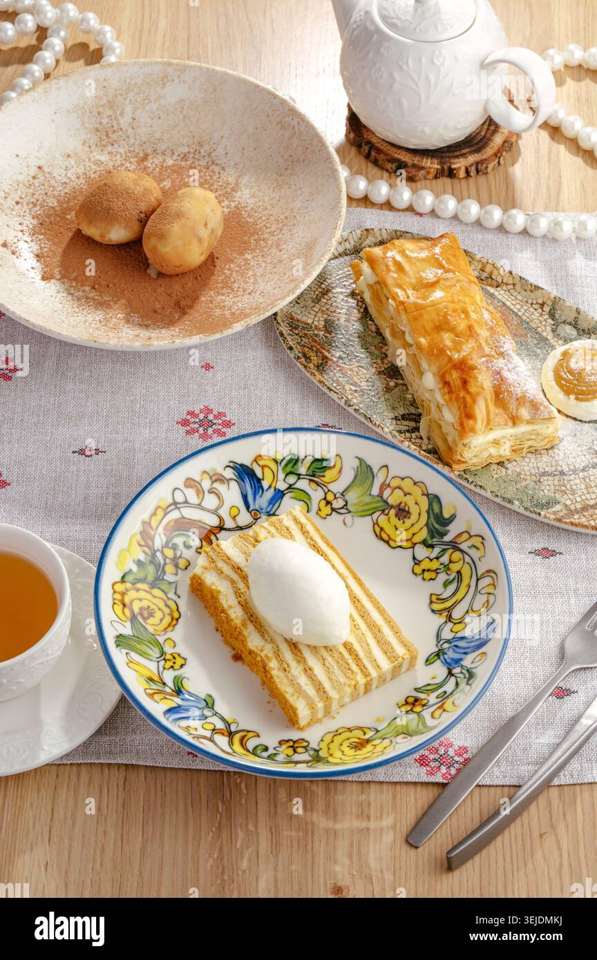 Un assortimento di deliziosi dessert e tè su un tavolo di legno Foto Stock