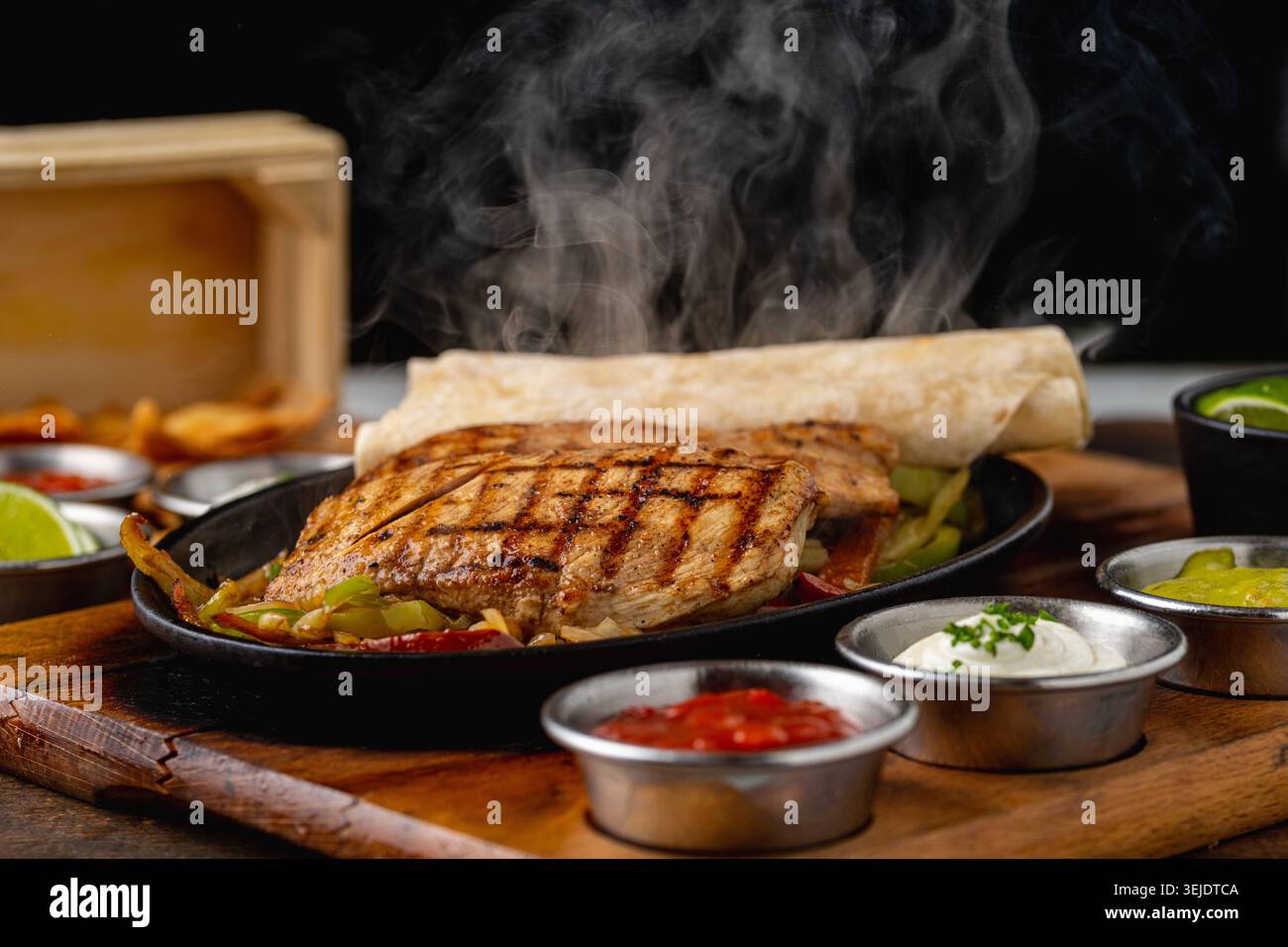 Fajita di pollo servita in padella con tortillas e condimenti piccanti Foto Stock