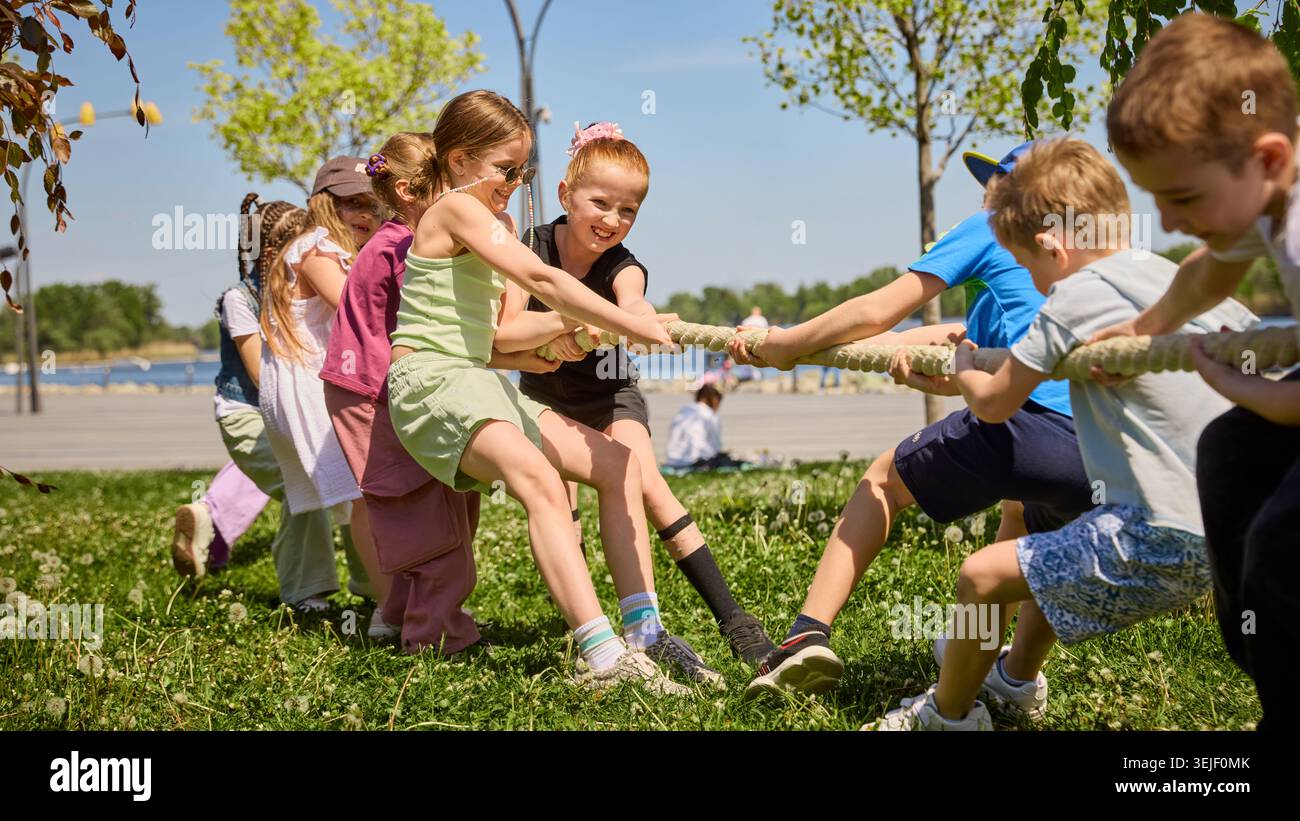 I bambini giocano a tiro di guerra sull'erba durante le assolate partite estive all'aperto. Foto Stock