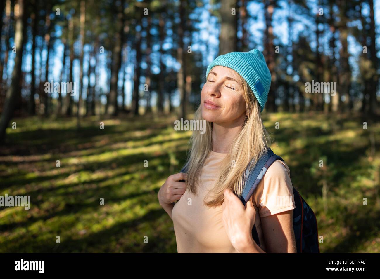 Donna calma in piedi a occhi chiusi nella foresta autunnale, godendo di silenzio e relax. Guarigione mentale Foto Stock
