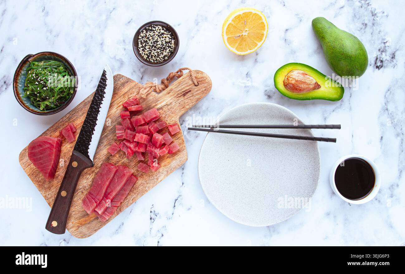 Cuocere il tonno fresco con ingredienti su un ripiano di marmo, ingredienti per preparare sushi e tartare di tonno Foto Stock