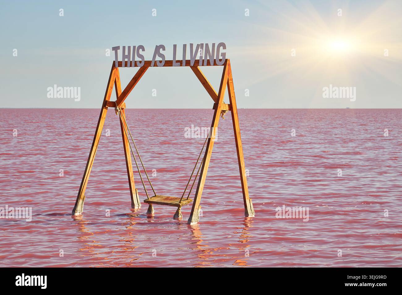 Un'altalena di legno parzialmente sommersa in un vivace lago di sale rosa, con le parole CHE VIVE sopra di esso. Paesaggio insolito e suggestivo. Foto Stock