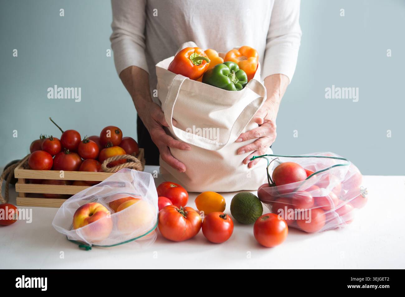 Mani anziane che tengono una cassa con pomodori freschi. imballaggio ecologico. concetto di acquisto zero rifiuti. Foto Stock