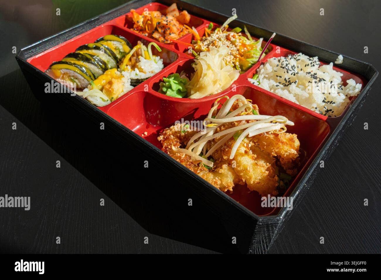 Pranzo giapponese al Bento Box con squilli di merluzzo fritti, sushi Rolls, insalata, riso, zenzero e wasabi sottaceto, involtini di pesce Maki, pesce giapponese, specialità di pesce asiatiche Foto Stock